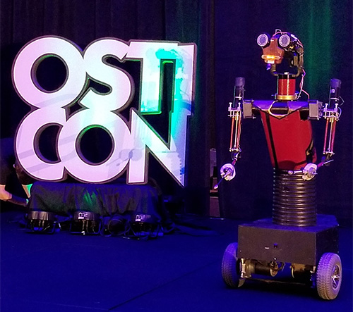 A photo of the OSTI-CON stage logo lit up while a robot was performing on stage.
